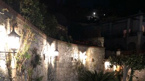 A stone pathway with decorative lighting, surrounded by greenery and a stone wall. - Villa Amalu Capri private pool (Capri)