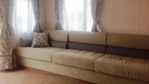 A living room with a beige sofa, patterned curtains, and a window with a view.