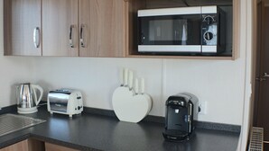A kitchen with a microwave, toaster, kettle, and coffee maker on the counter.