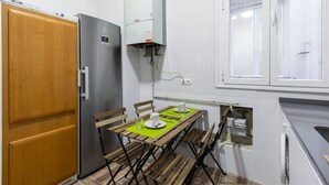 Une cuisine de taille réduite avec une table en bois, un réfrigérateur et une fenêtre.