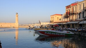 Una zona sul lungomare con un'imbarcazione chiamata 'Parasailing' ormeggiata vicino a un edificio con posti a sedere all'aperto.
