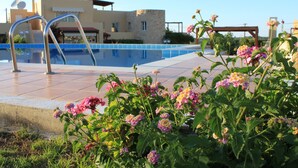 Una piscina con scala in metallo, immersa nel verde e tra fiori.