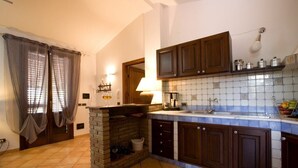 Una cocina con chimenea de piedra, armarios de madera y salpicadero de azulejos.
