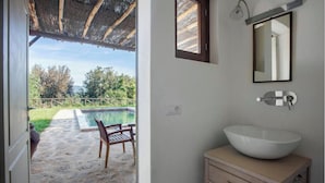 Une salle de bain avec un grand lavabo blanc, un miroir et une fenêtre donnant sur un espace piscine.
