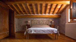 Une chambre avec un plafond en bois, un cadre de lit en métal, un plancher en bois, un radiateur et une armoire en bois.