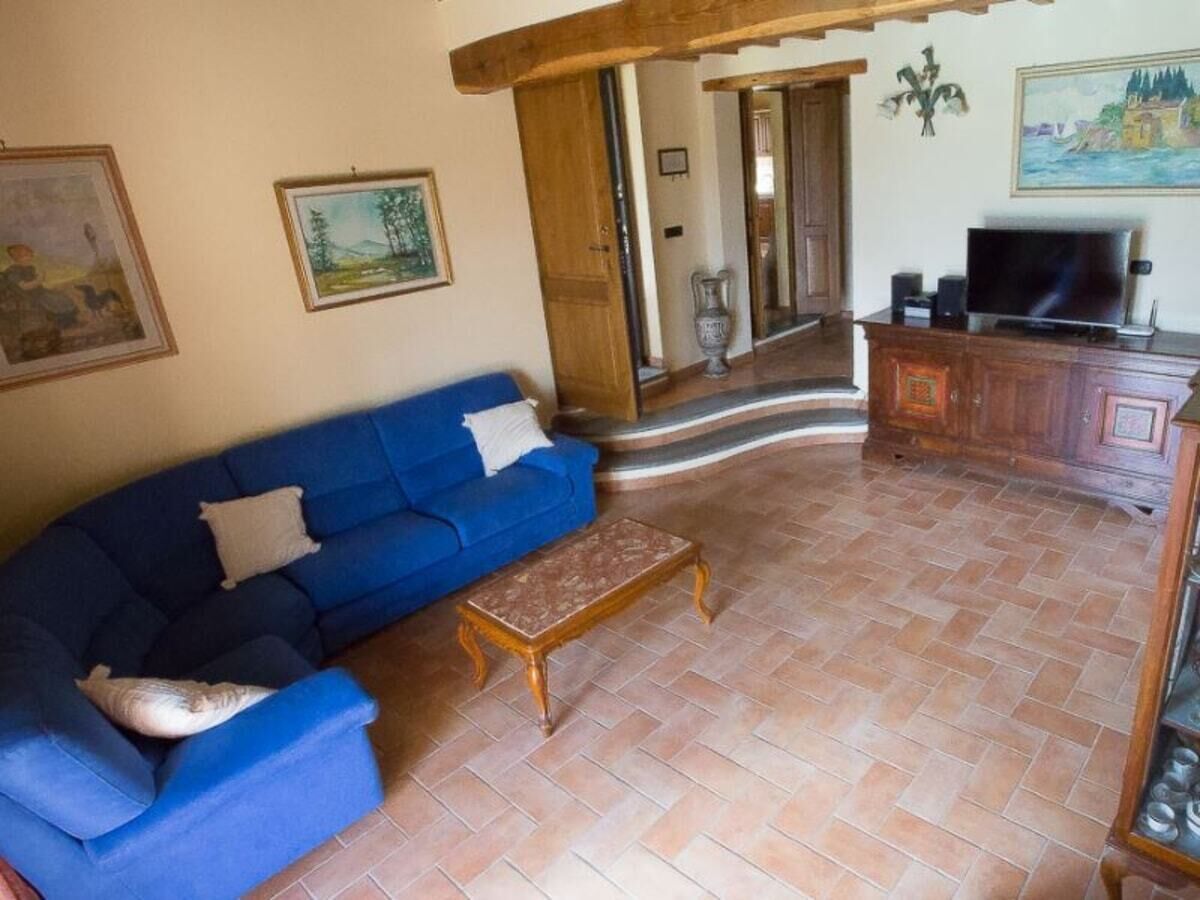 A living room with a blue sofa, a wooden coffee table, and a television on a wooden cabinet.