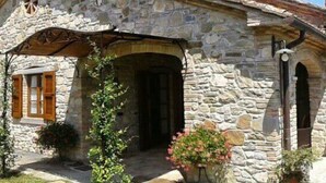 Une maison en pierre avec un toit en pente, une porte en bois et un petit porche.