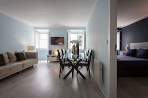 A modern living room with a glass dining table, a sofa, a TV, and a bed. - Apartment with a private terrace in Bairro Alto (Lisboa)