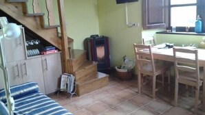 Une cuisine compacte comprenant une table à manger, des chaises, une cuisinière encastrée et un petit réfrigérateur.