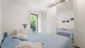 A bedroom with two beds, a dresser, a mirror, and a window with curtains. - FARMHOUSE ANTICO BORGO GARDEN (COLICO)