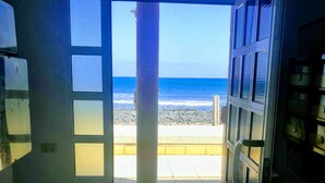 Ein Zimmer mit großem Fenster und Blick auf einen Strand.