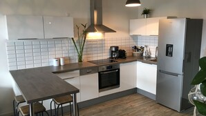 Eine moderne Küche mit Kochinsel, integriertem Backofen und Edelstahlkühlschrank.