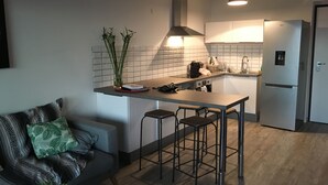 Eine moderne Küche mit einer zentralen Kochinsel, Barhocker, einem Einbauofen und einem Kühlschrank.