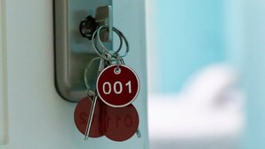 Een sleutelhanger met een rode sleutel en een metalen sleutelring, bevestigd aan een deurslot.
