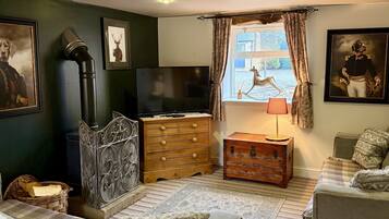 A cozy room with a bed, a dresser, a television, and a window with curtains.