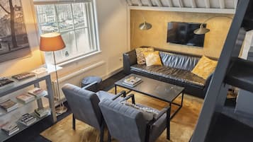Relax in this stylish living room with a sofa, armchairs, and a glass coffee table, offering a view of the city.
