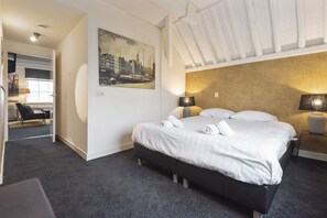 A hotel room with a bed, bedside lamps, a painting on the wall, and a desk with a chair. - Spaarne Luxury Residence Haarlem (Haarlem)