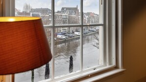 Ventana con vistas a un canal y edificios, una lámpara a la izquierda y cielo despejado.