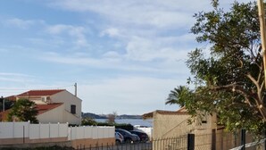 Ein eingezäunter Parkplatz mit blauem Himmel und Gebäuden in der Ferne.