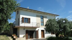 Une maison à deux étages avec un balcon, une porte d’entrée et un petit jardin.