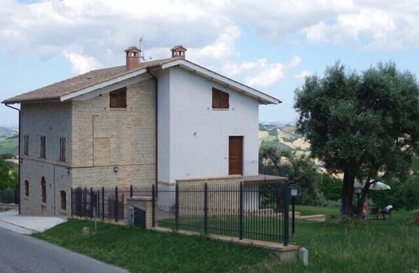 Un edificio de dos pisos con fachada de piedra y sección superior blanca.