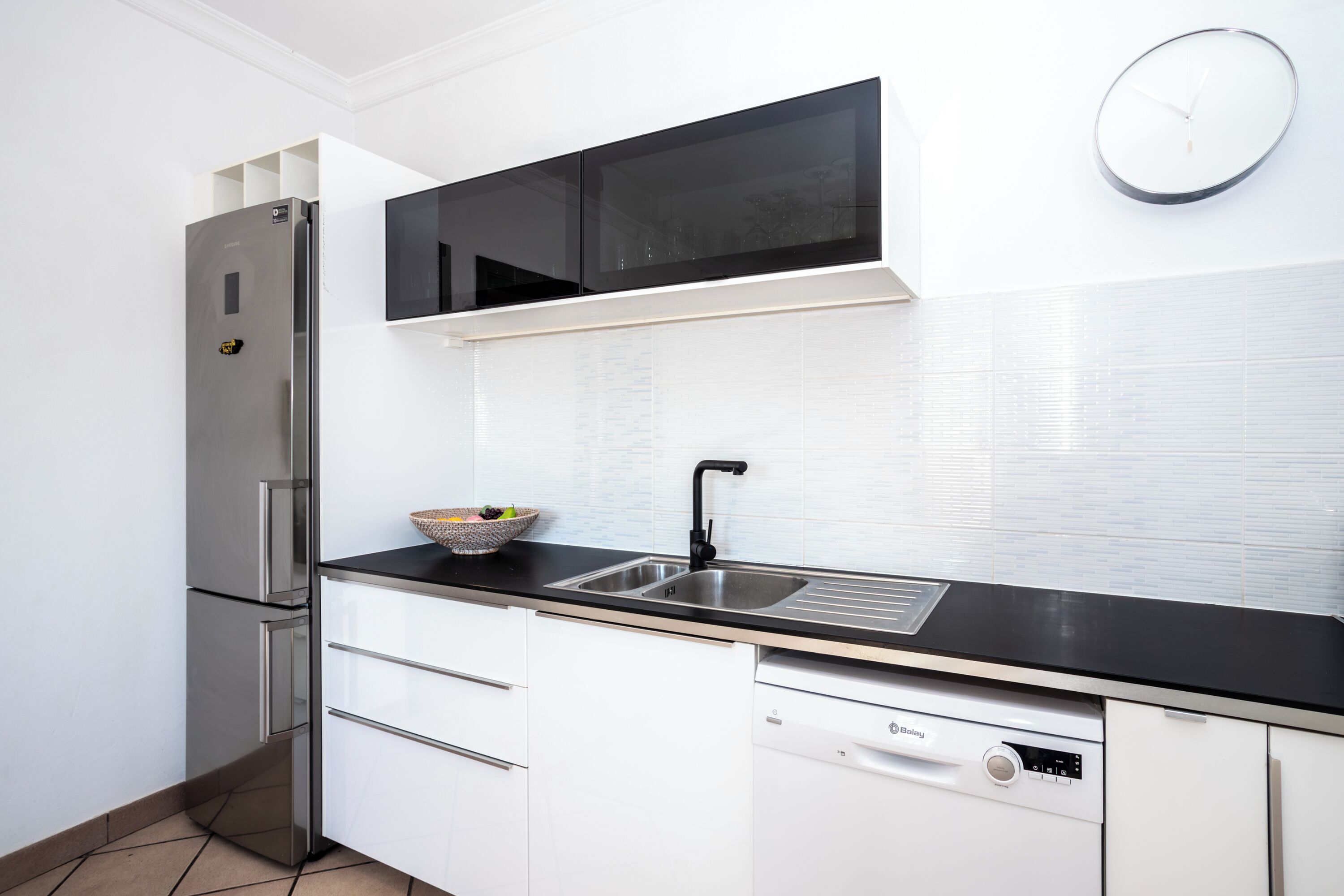 A modern kitchen with a stainless steel refrigerator, a black microwave, and a dishwasher.