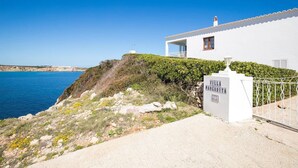 A white villa with a balcony overlooking a coastal area.