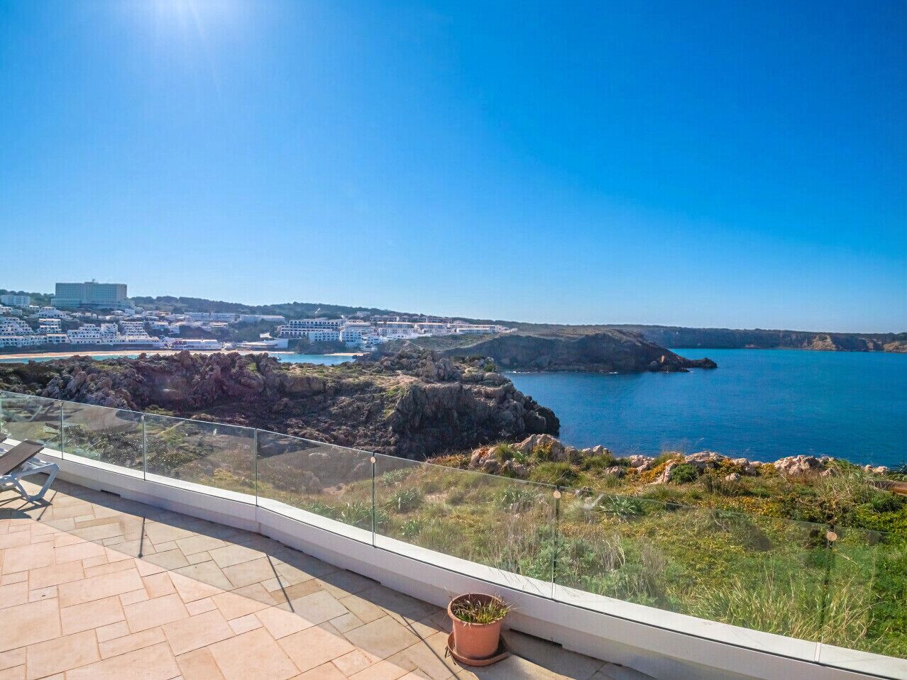 Un balcon offrant une vue dégagée sur un paysage côtier, comprenant des formations rocheuses et une étendue d’eau.