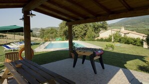 Un espace extérieur abrité comprenant une piscine, des chaises longues et une table de baby-foot.