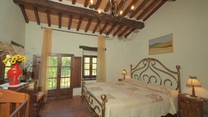 Une chambre avec un plafond en bois, un lit avec une tête de lit, une table de chevet, une lampe et une fenêtre avec des rideaux.