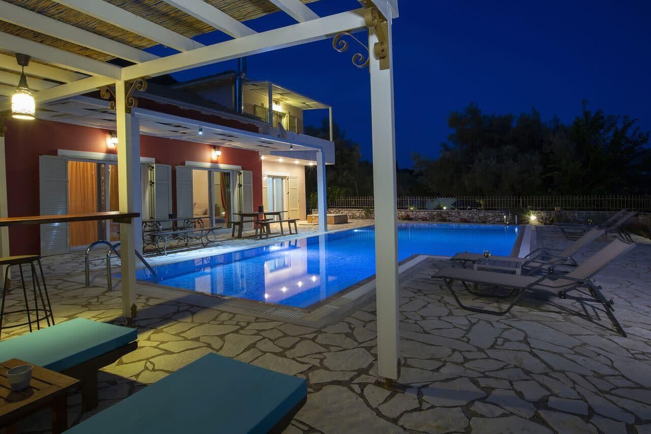 A pool area with lounge chairs, a table, and a covered seating area.