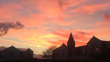 Une église dotée d’un clocher imposant et surmontée d’une croix, entourée d’immeubles d’habitation, le tout baigné par les couleurs du coucher de soleil.