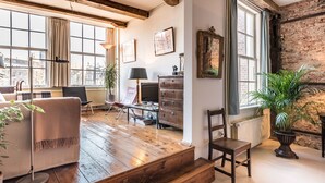 Ein gemütliches Wohnzimmer mit Holzboden, Kamin, großem Fenster und Blick auf die Stadt.