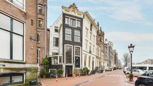 Eine Reihe traditioneller europäischer Gebäude mit Ziegel Fassade, ein schwarz-weißes Gebäude mit verziertem Eingang und eine Straße mit parkenden Autos und einem Laternenpfahl.