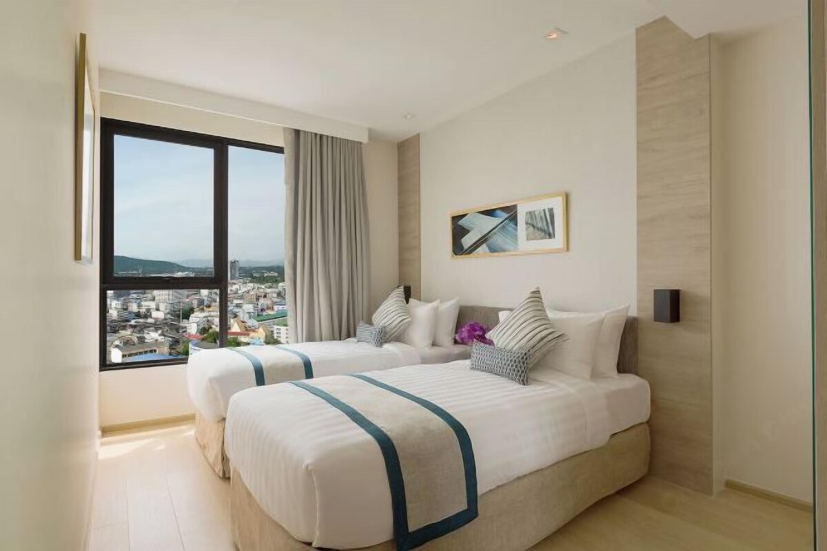 A hotel room with two beds, a large window with a view, and a framed picture on the wall.