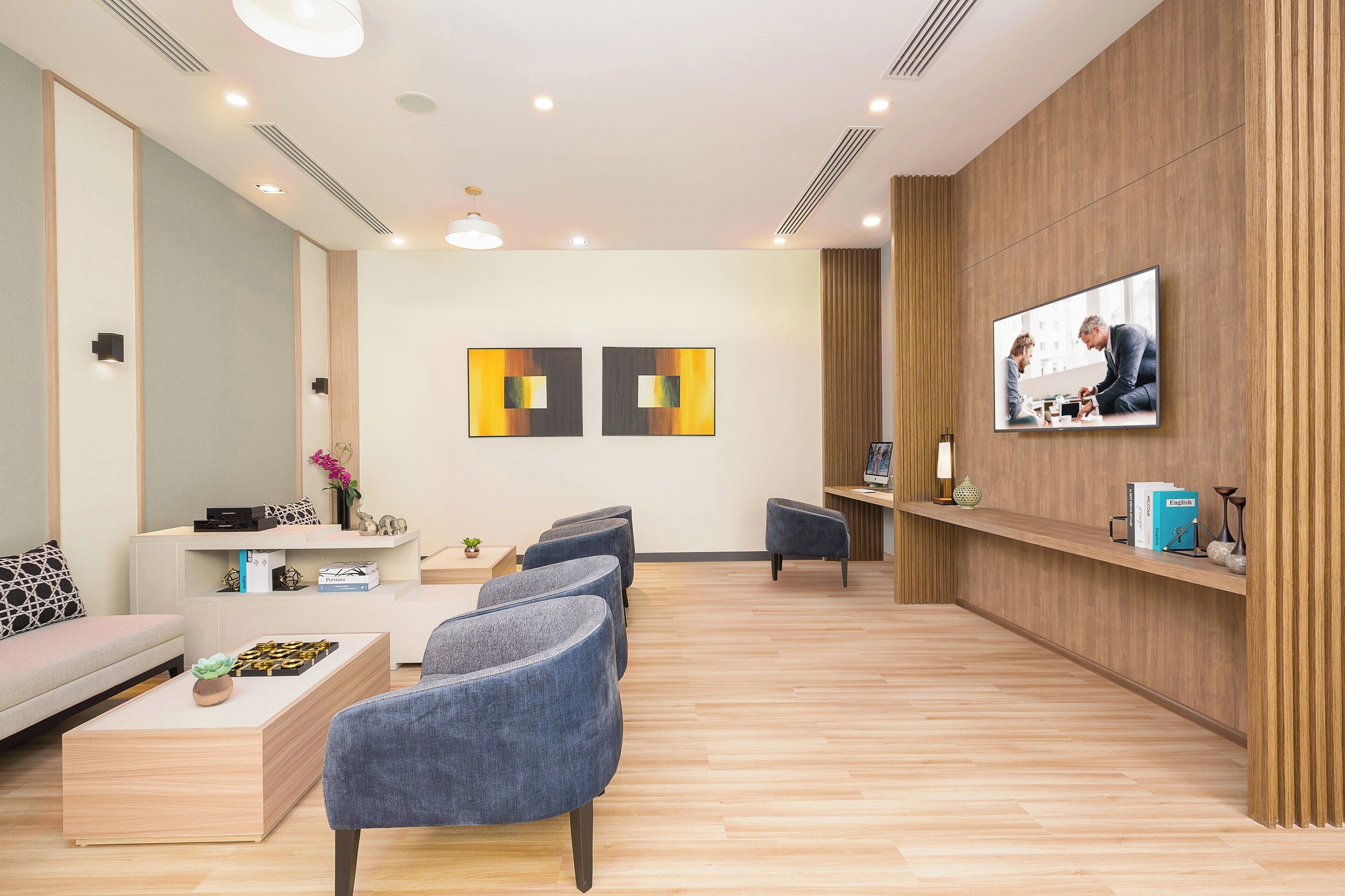 Een moderne wachtruimte met een bank, stoelen, een salontafel en een aan de muur bevestigde televisie.
