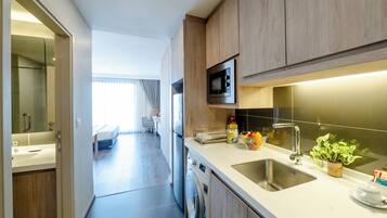 A modern kitchen with wooden cabinets, a built-in microwave, a stainless steel sink, and a washing machine.