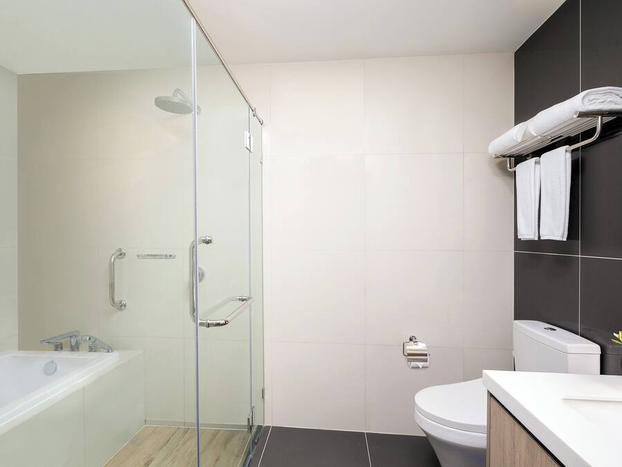A modern bathroom with a glass-enclosed shower, a white bathtub, a toilet, and a sink with a countertop.