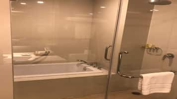 A modern bathroom with a glass-enclosed shower, a bathtub, and a glass door.