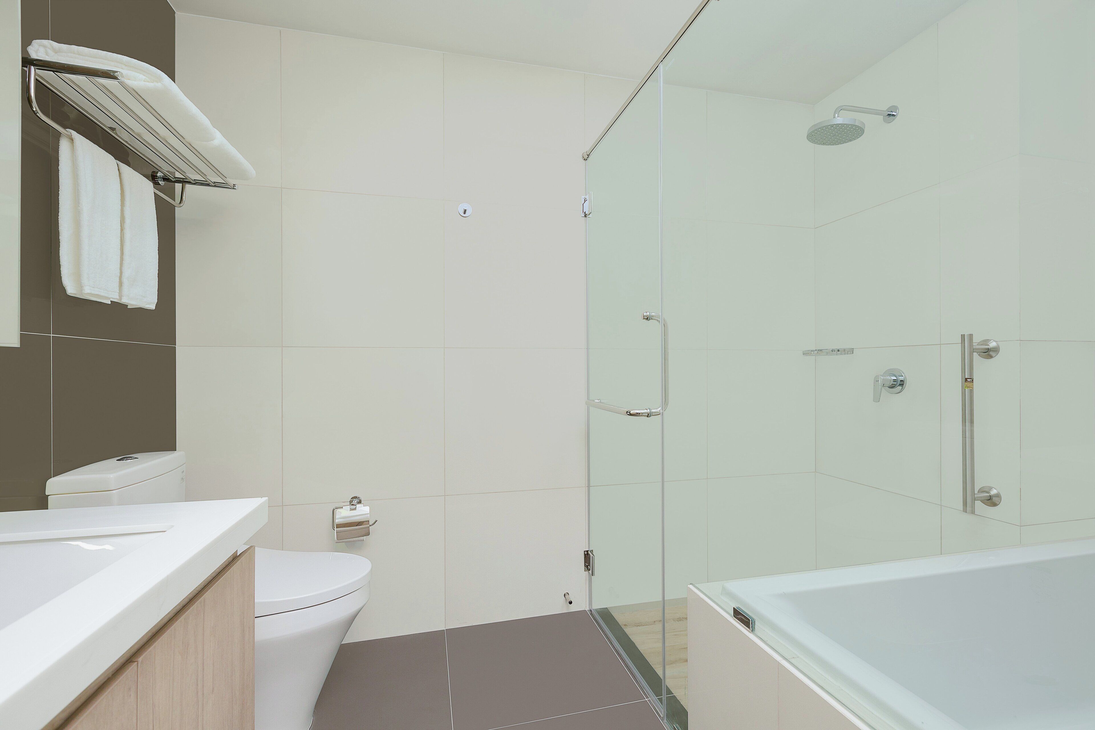 Une salle de bain moderne avec une douche à parois de verre, une baignoire blanche et des toilettes.