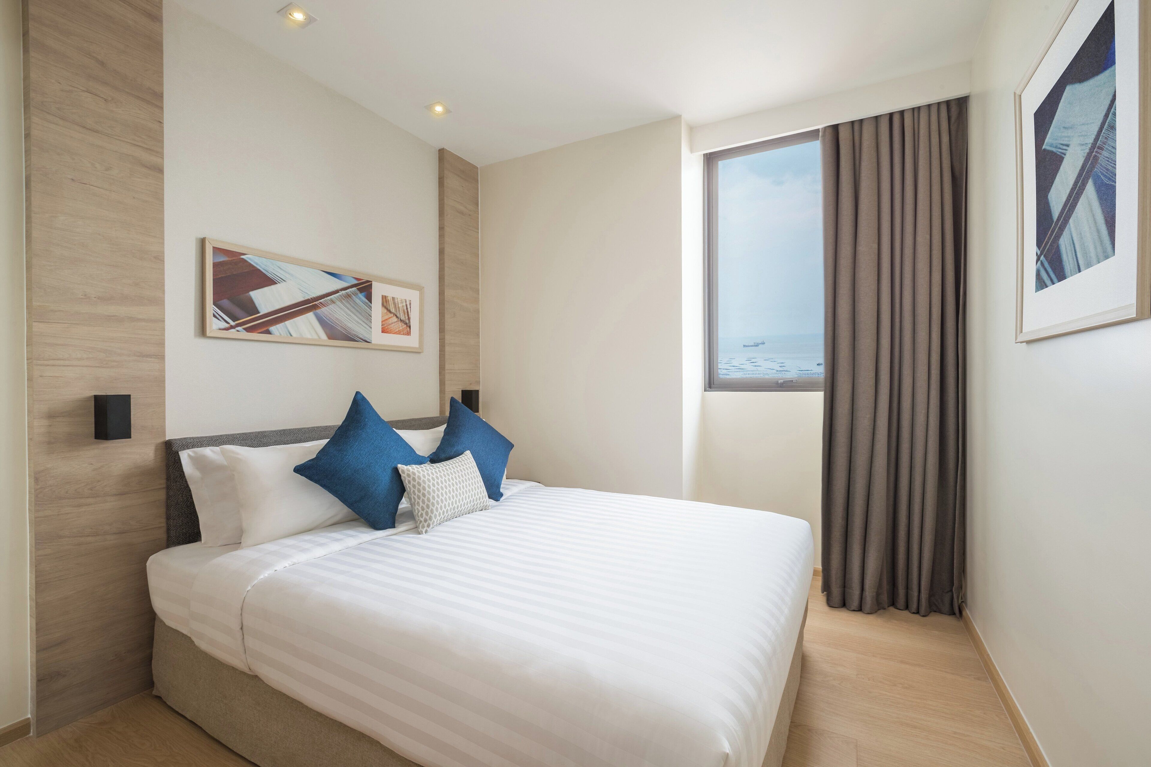 Una habitación de hotel moderna con una cama grande, vista al mar y un cuadro enmarcado en la pared.