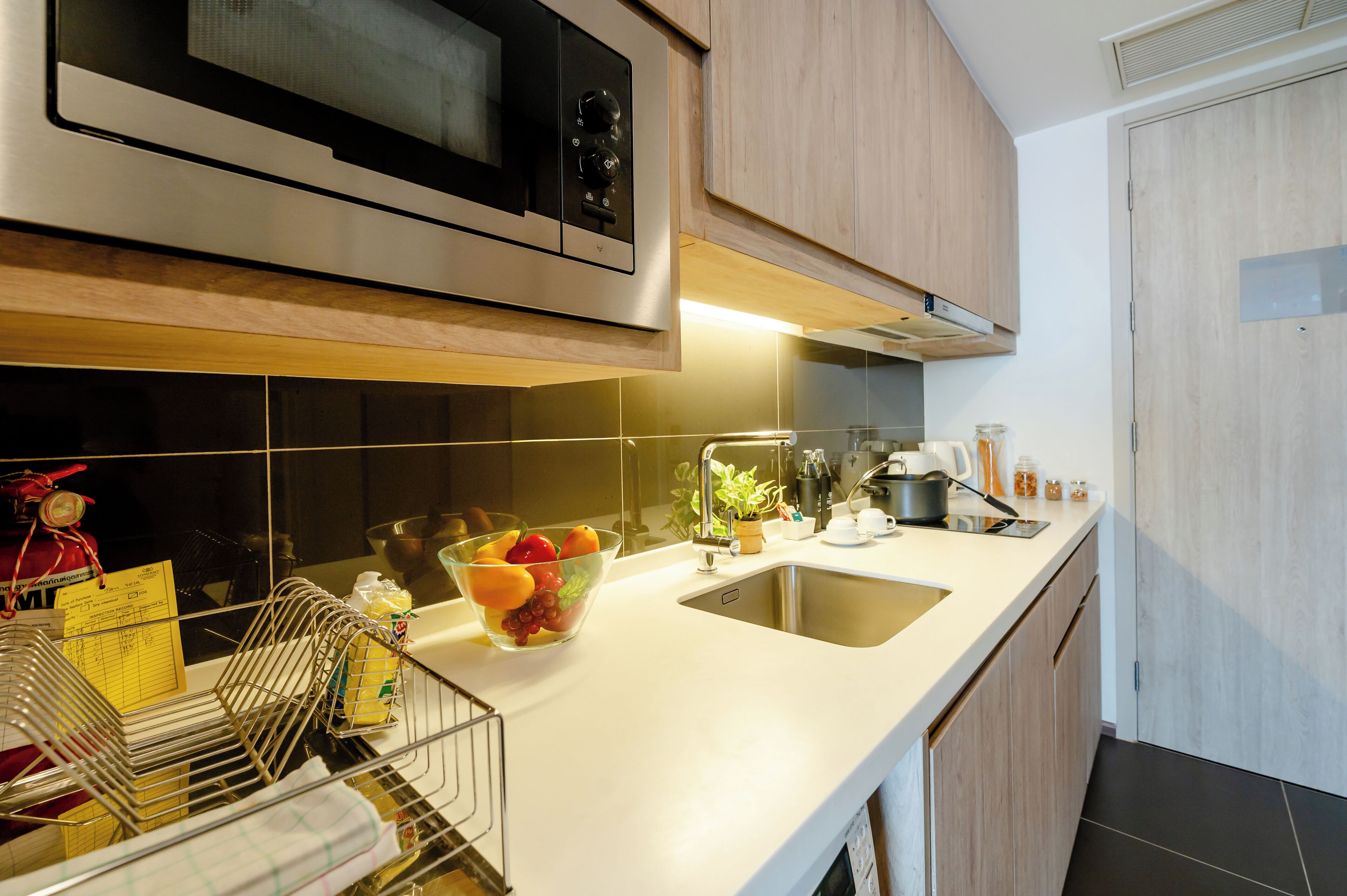 A modern kitchen with stainless steel appliances, a white countertop, and wooden cabinets.