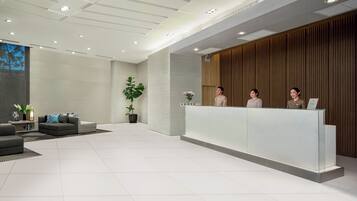 Un área de recepción moderna con un escritorio de cristal, un sofá y una planta en maceta.