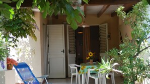 A covered patio area with a table and chairs, a blue folding chair, and potted plants. - Casa Catalogna A, Historic Center of Lipari (Lipari)