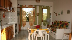 A compact kitchen with a dining table and chairs, a sofa, and a fan. - Casa Catalogna A, Historic Center of Lipari (Lipari)