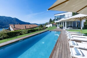 Ein Schwimmbad mit Holzterrasse, Liegestühlen und Bergblick.