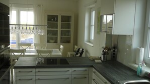 Una cucina moderna con mobili bianchi, un'isola centrale e un'area da pranzo con tavolo e sedie.