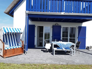 A blue and white building with a balcony, a table with chairs, and a striped beach chair. - Cozy, modern, child-friendly vacation home with large garden (Vaschwitz)