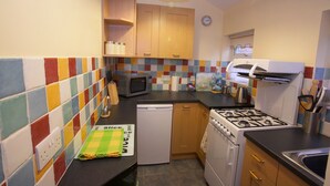 A compact kitchen with a microwave, stove, and dishwasher. - Saltburn Holidays Primrose Cottage (Guisborough)