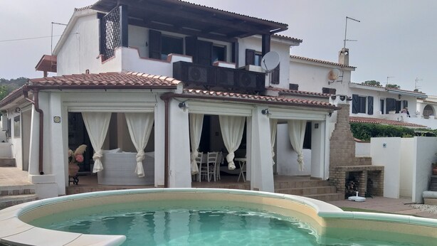Une villa moderne dotée d’une piscine, d’un espace extérieur aménagé et d’une cheminée en briques.